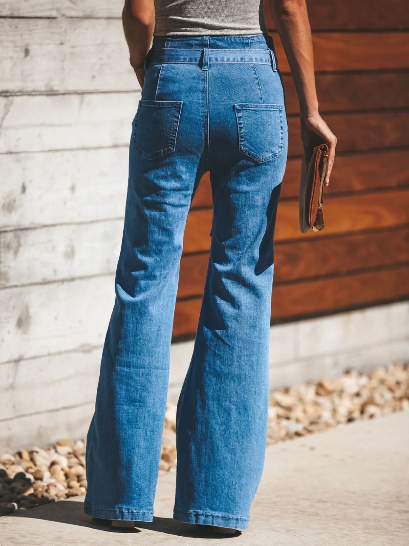 NEWYORKLISTED STYLE COLLECTION: Person wearing blue jeans standing against a wooden wall.