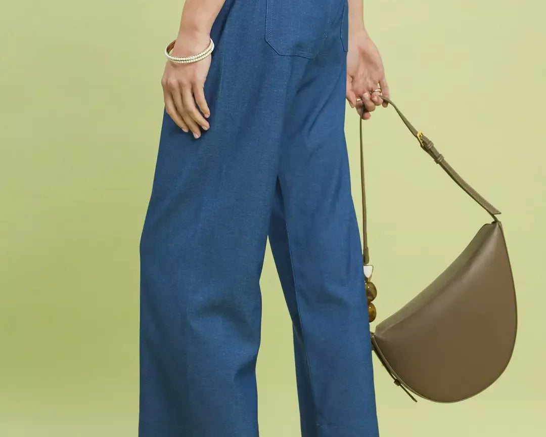 NEWYORKLISTED Style Collection: Person wearing blue pants and holding a brown handbag on a light green background