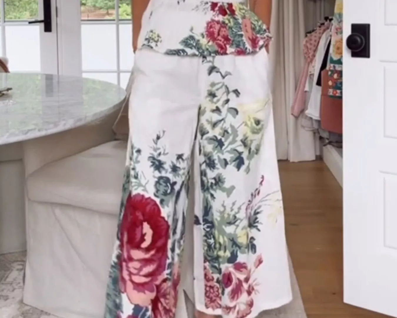 NEWYORKLISTED STYLE COLLECTION: Person wearing a floral strapless top and wide-leg pants in a home setting.