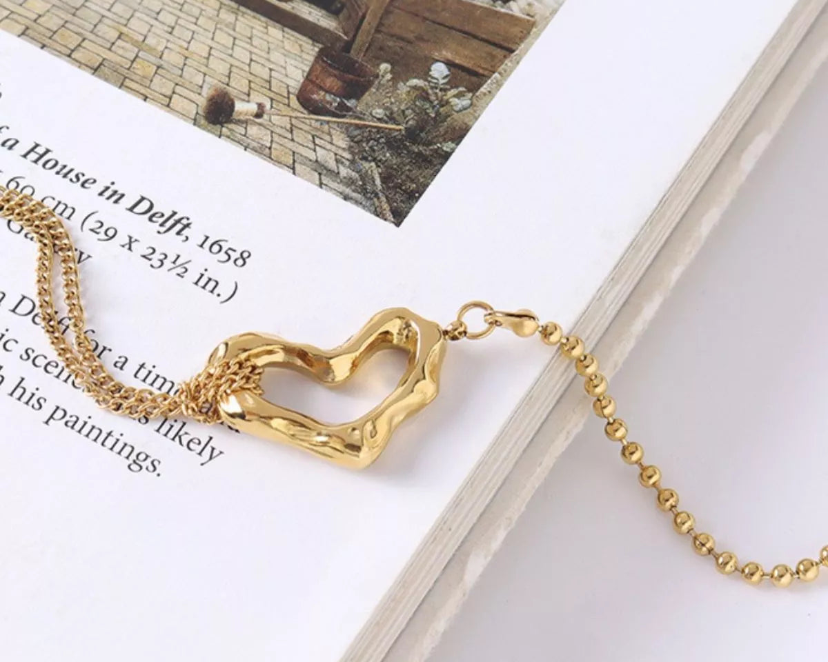 NYLD Glamour Collection by NEWYORKLISTED: Gold bracelet with a heart-shaped clasp on a book page