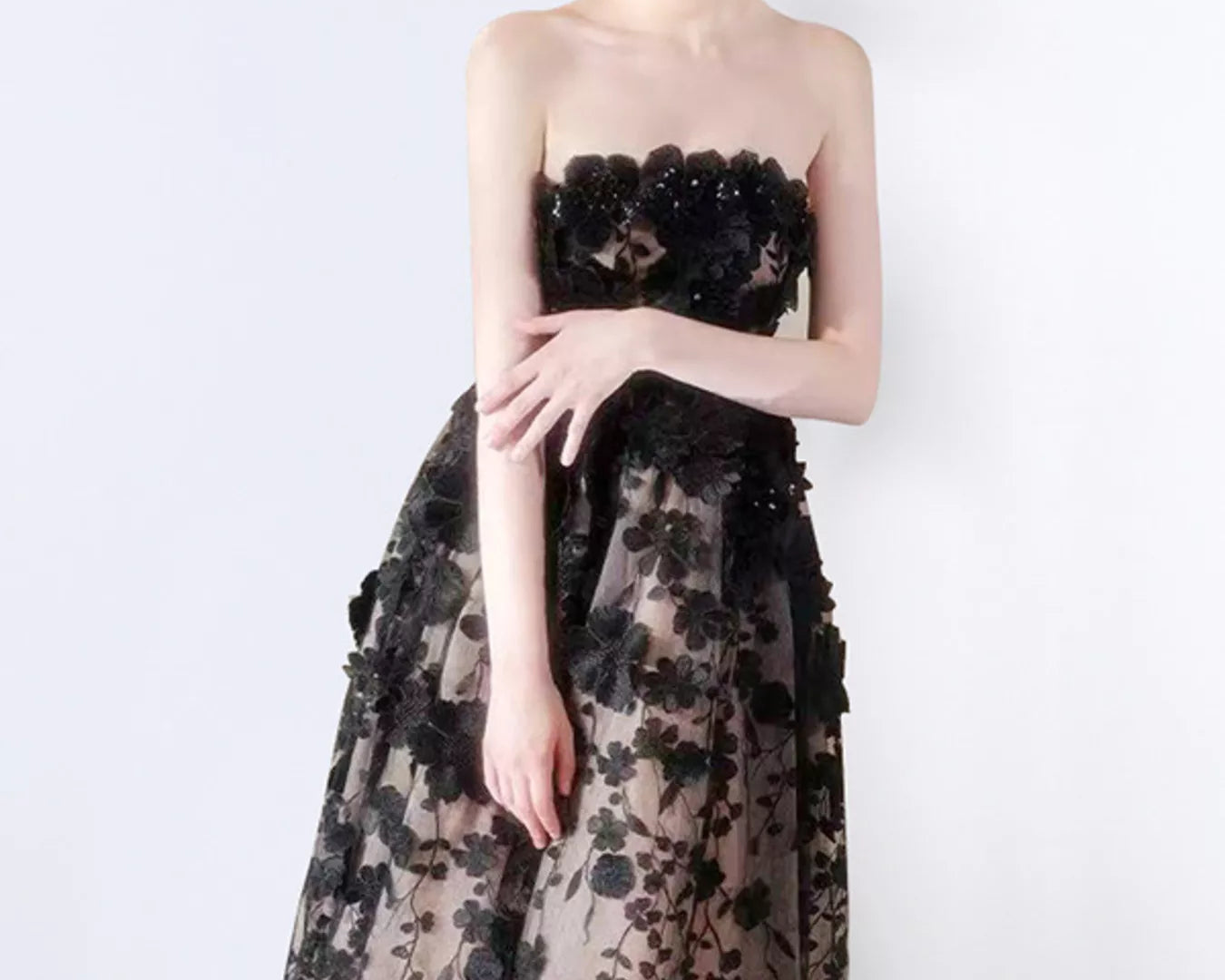 NEWYORKLISTED STYLE COLLECTION: Woman wearing a black floral strapless gown on a white background