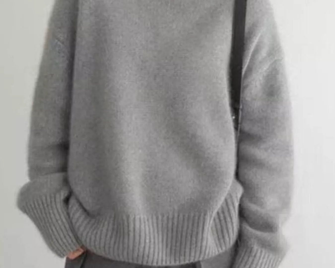 Person wearing a gray turtleneck sweater against a plain background