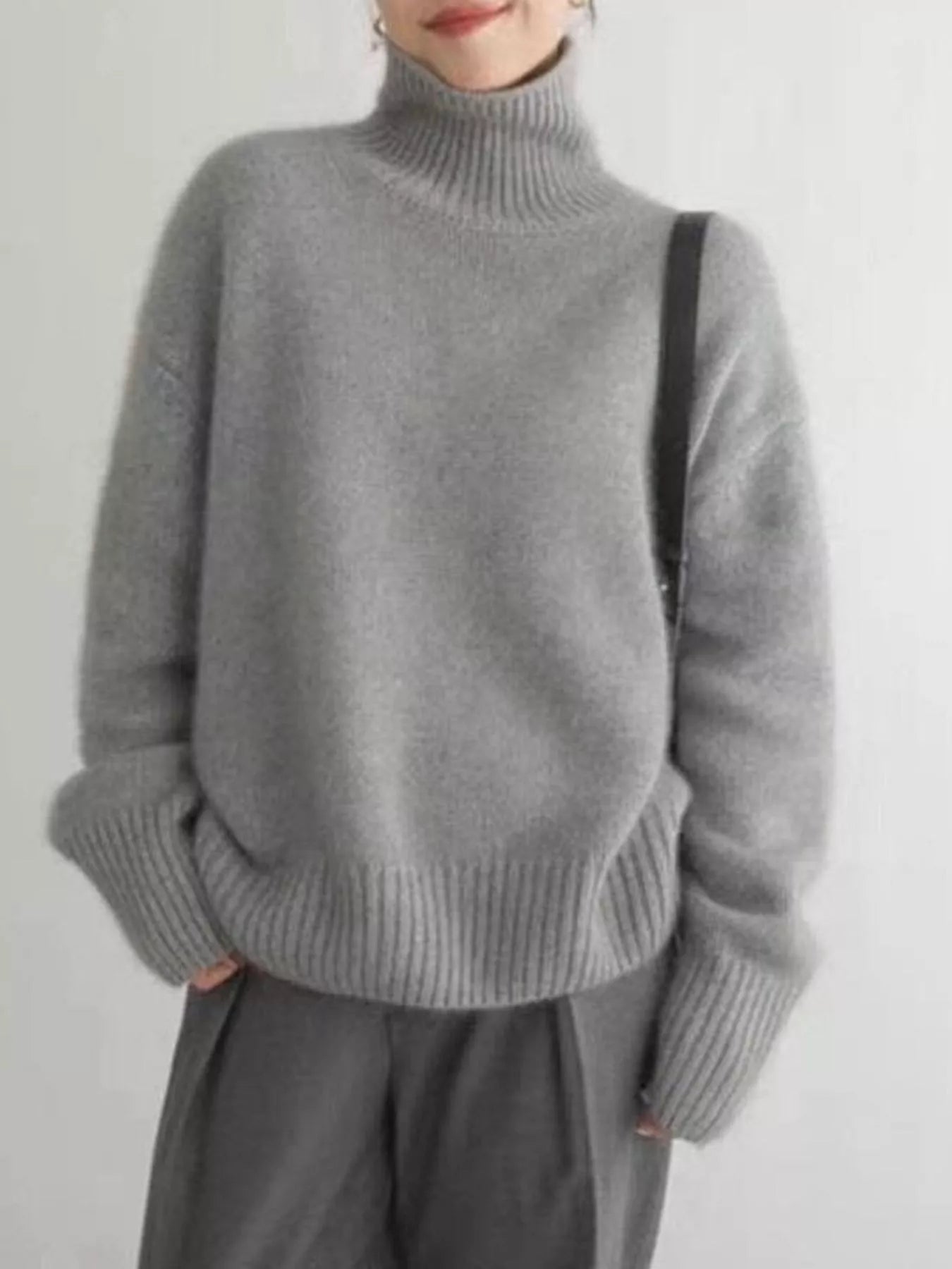Person wearing a gray turtleneck sweater against a plain background