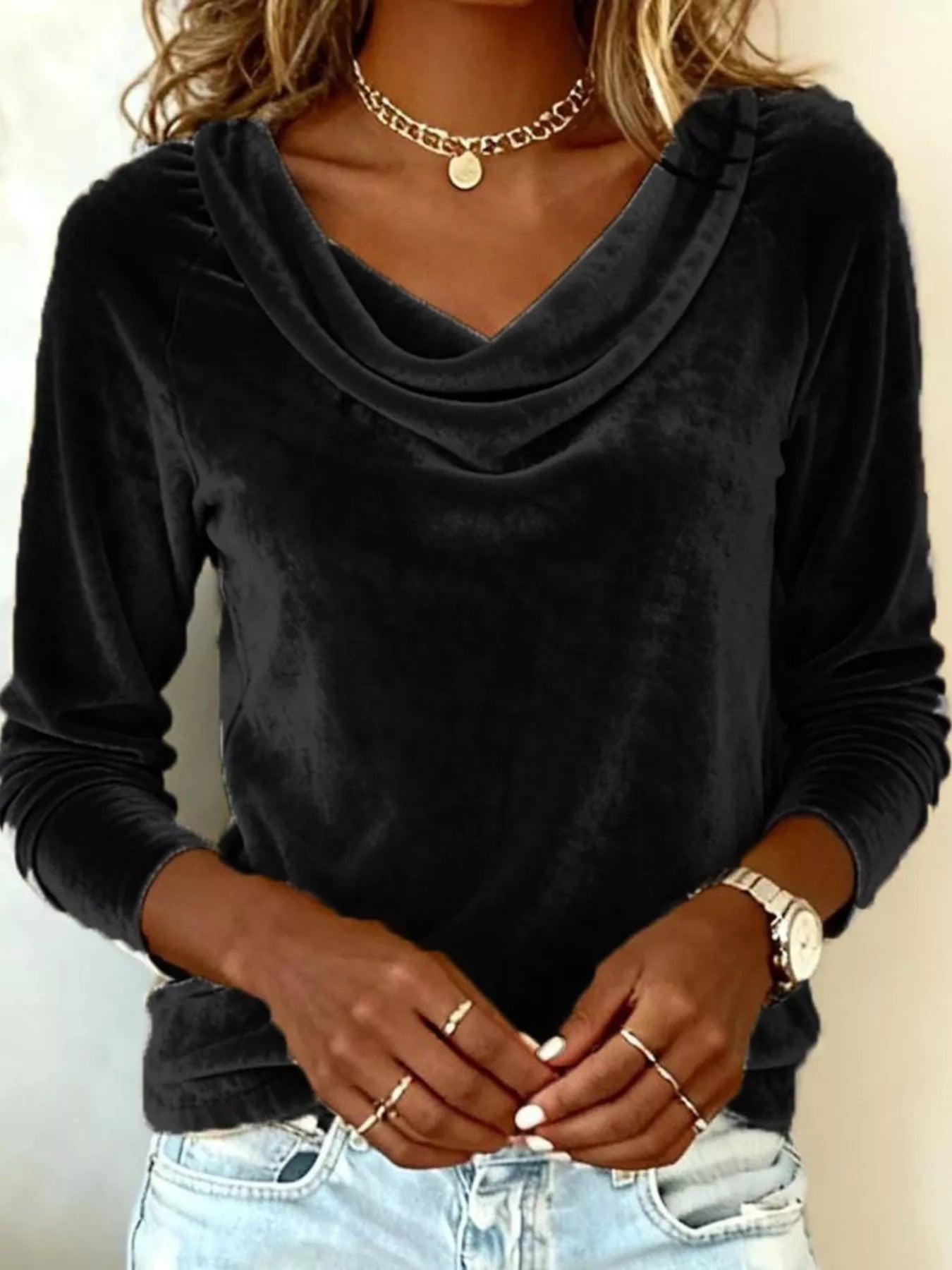 NEWYORKLISTED STYLE COLLECTION: Person wearing a black long-sleeve top with a cowl neckline, gold jewelry, and light blue jeans.