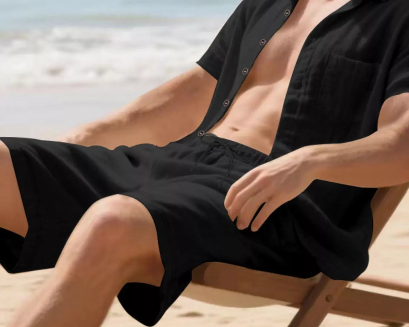 NEWYORKLISTED ATLAS MEN'S COLLECTION: Man in black shirt and shorts relaxing on a beach chair with ocean view