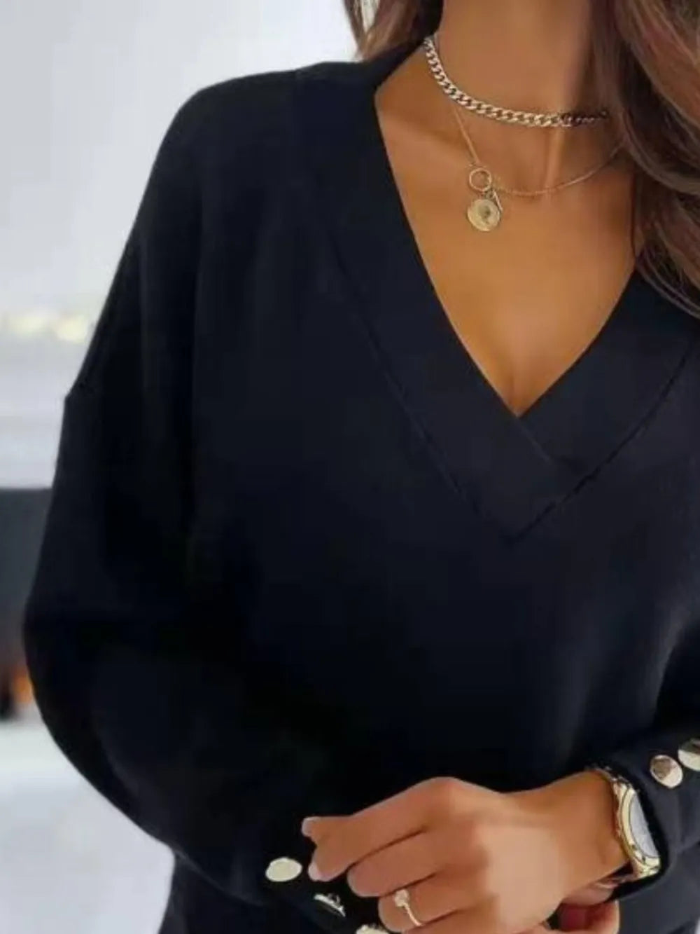 NEWYORKLISTED STYLE COLLECTION: Person wearing a black outfit with gold jewelry and a blurred background