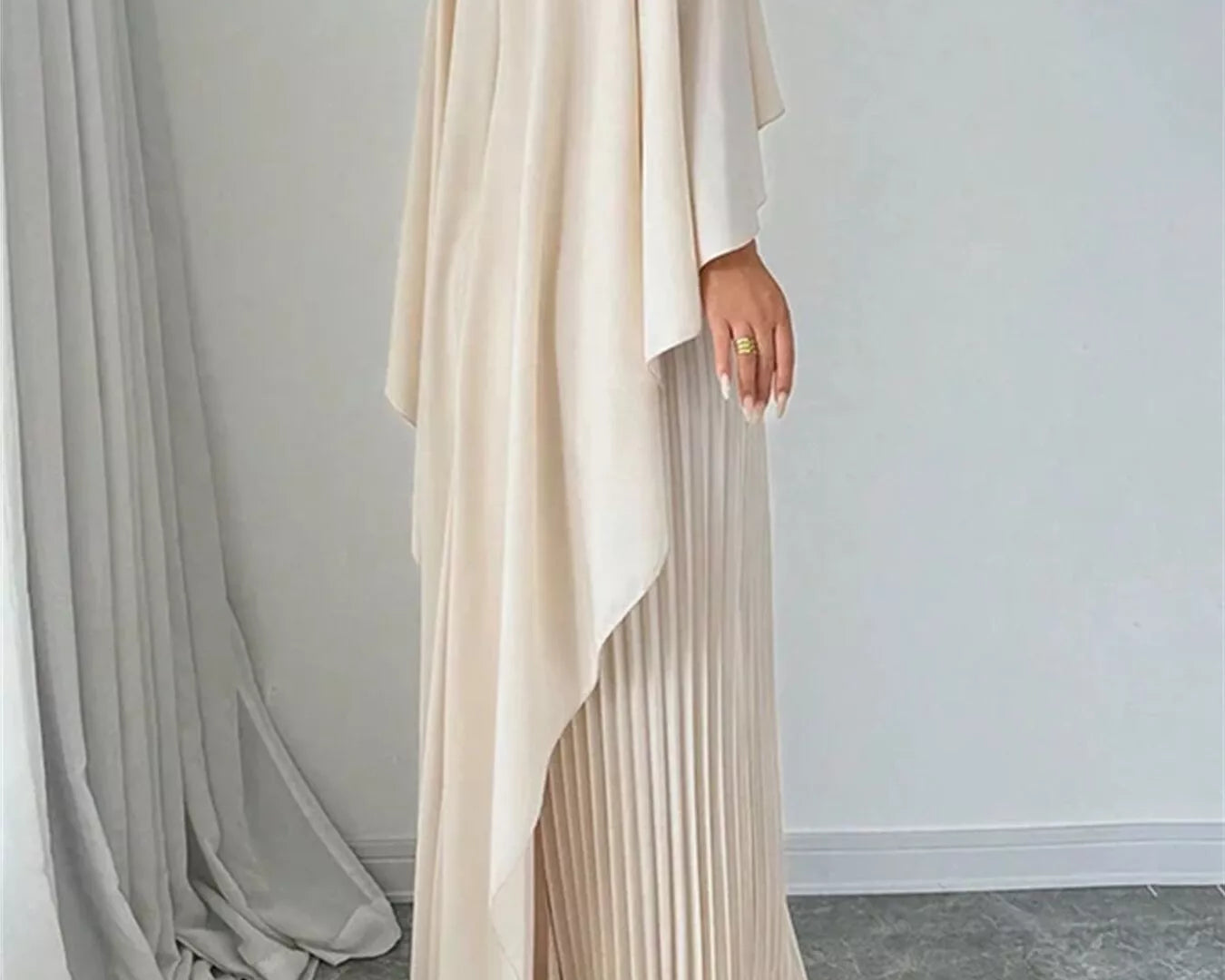 NEWYORKLISTED STYLE COLLECTION: Beige long dress with pleated skirt against a plain background