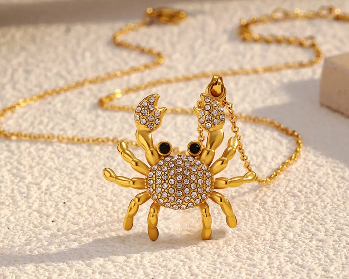 NYLD Glamour Collection by NEWYORKLISTED: Gold crab-shaped pendant necklace on a light background