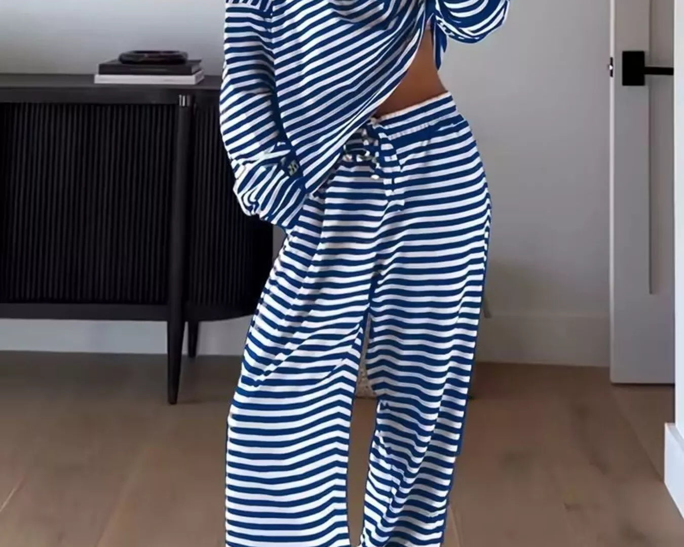 NEWYORKLISTED Comfort Collection: Person wearing a blue and white striped outfit in a room with wooden flooring and a black cabinet.