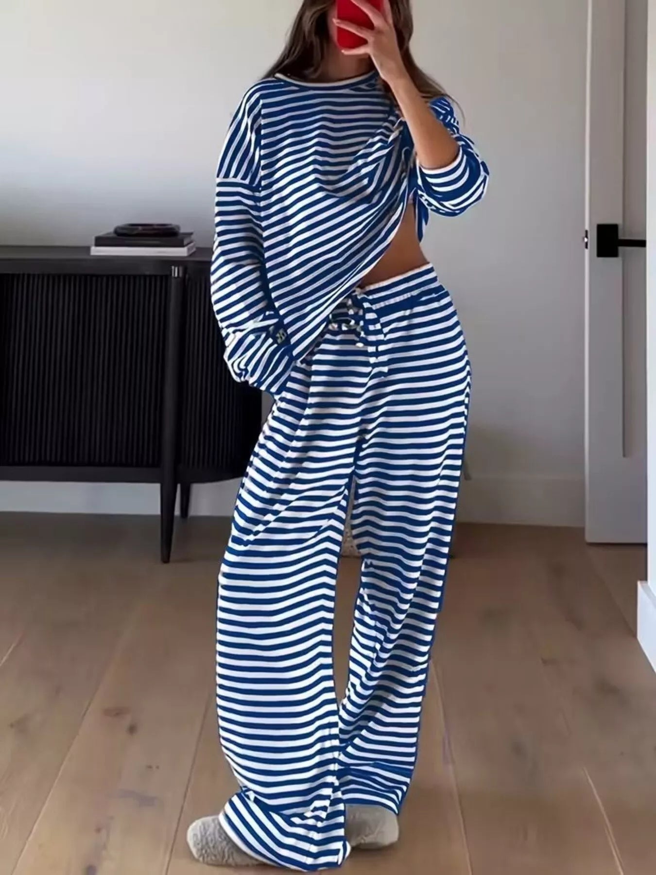 NEWYORKLISTED Comfort Collection: Person wearing a blue and white striped outfit in a room with wooden flooring and a black cabinet.