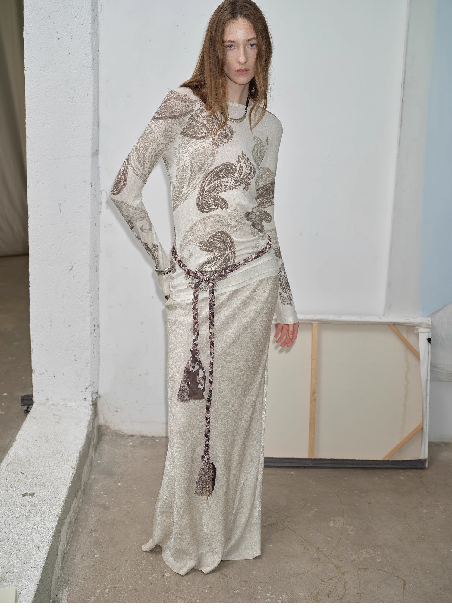 NEWYORKLISTED STYLE COLLECTION: Woman wearing a long, patterned dress with a white wall background