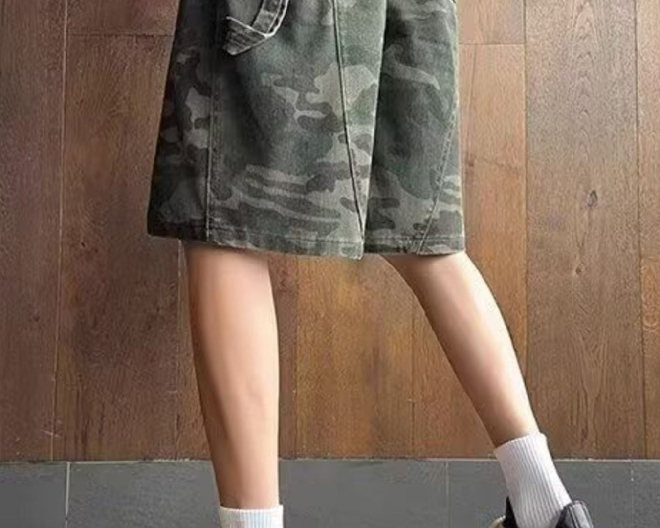 NEWYORKLISTED ATLAS MEN's COLLECTION: Person wearing camouflage shorts and black sneakers on a wooden floor.