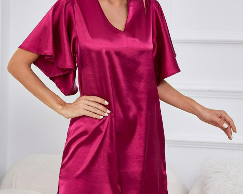 NEWYORKLISTED Intimate Apparel: Woman wearing a magenta satin nightgown in a cozy room.