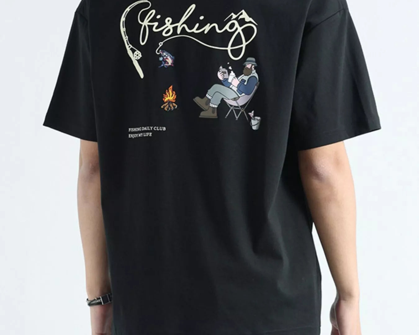 Person wearing a black t-shirt with fishing-themed graphics on the back, standing against a light gray background.