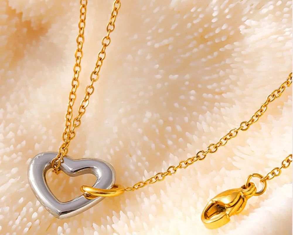 NEWYORKLISTED Valentine's Day Specials: Gold and silver heart-shaped necklace on a textured beige background