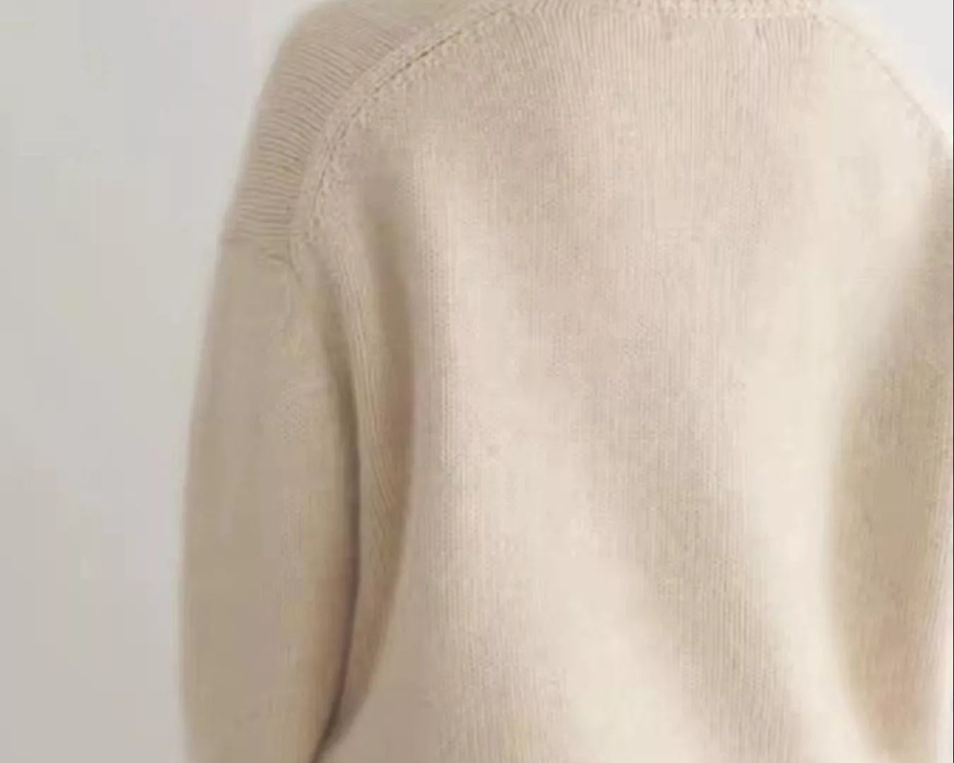 Person wearing a beige turtleneck sweater against a white background on NEWYORKLISTED.COM