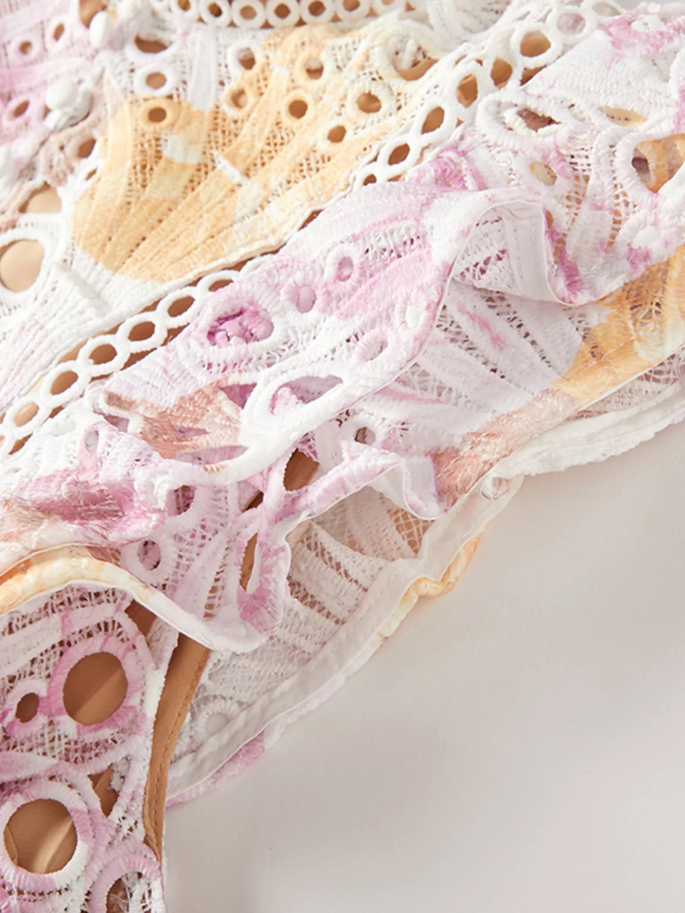 Close-up of a lace doily with pink and white patterns on a light background