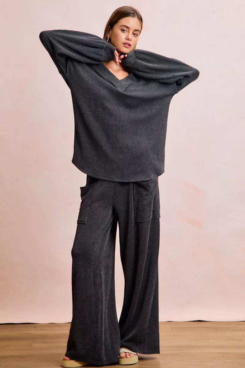 NEWYORKLISTED Comfort Collection: Person wearing a dark gray outfit with wide-legged pants against a plain background