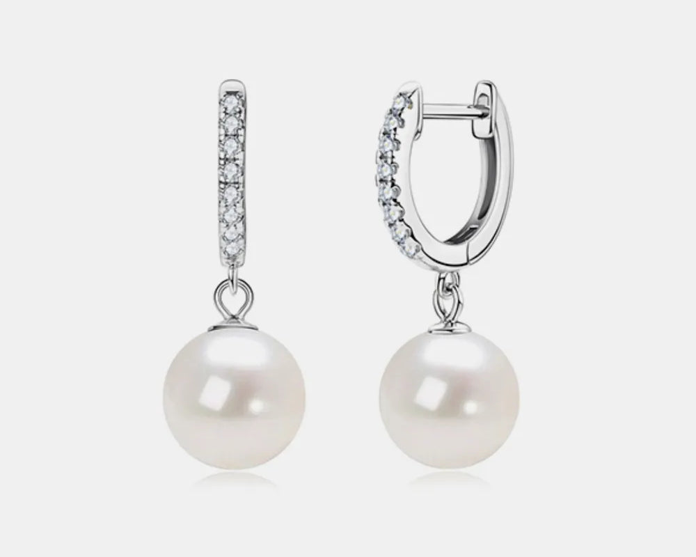NYLD GLAMOUR COLLECTION by NEWYORKLISTED: Pair of pearl earrings with silver hooks on a light gray background