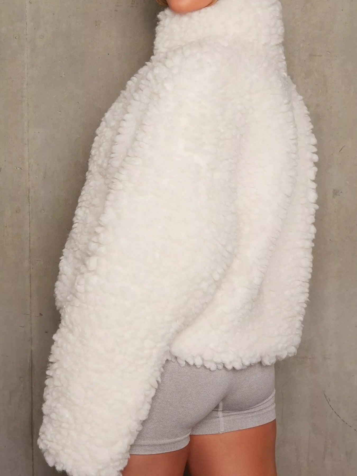 NEWYORKLISTED STYLE COLLECTION: White fluffy sweater over gray shorts against a neutral background