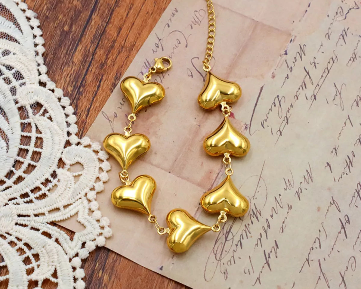 NYLD Glamour Collection by NEWYORKLISTED: Gold heart-shaped earrings on a wooden surface with lace and an old letter.