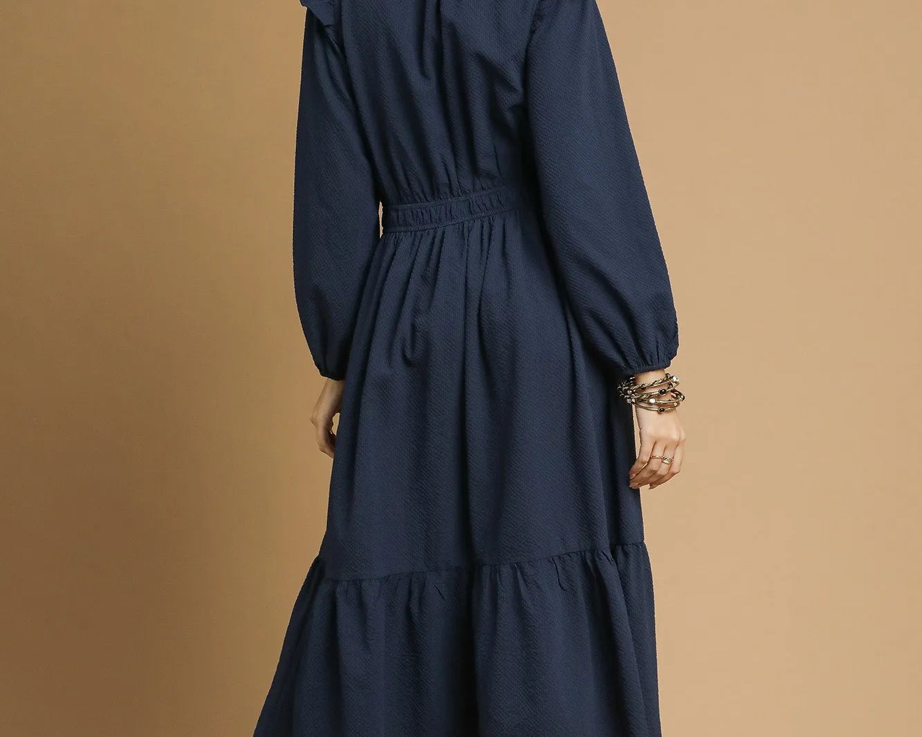 NEWYORKLISTED STYLE COLLECTION: Woman wearing a navy dress against a beige background