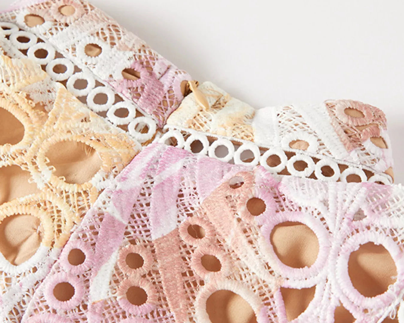 Close-up of lace fabric in pastel colors on a white background