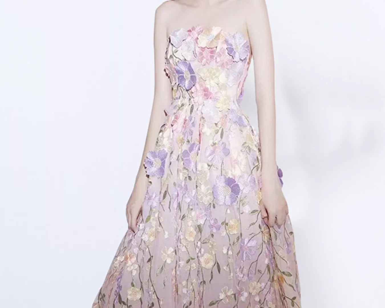 NEWYORKLISTED STYLE COLLECTION: Woman wearing a strapless floral dress on a white background