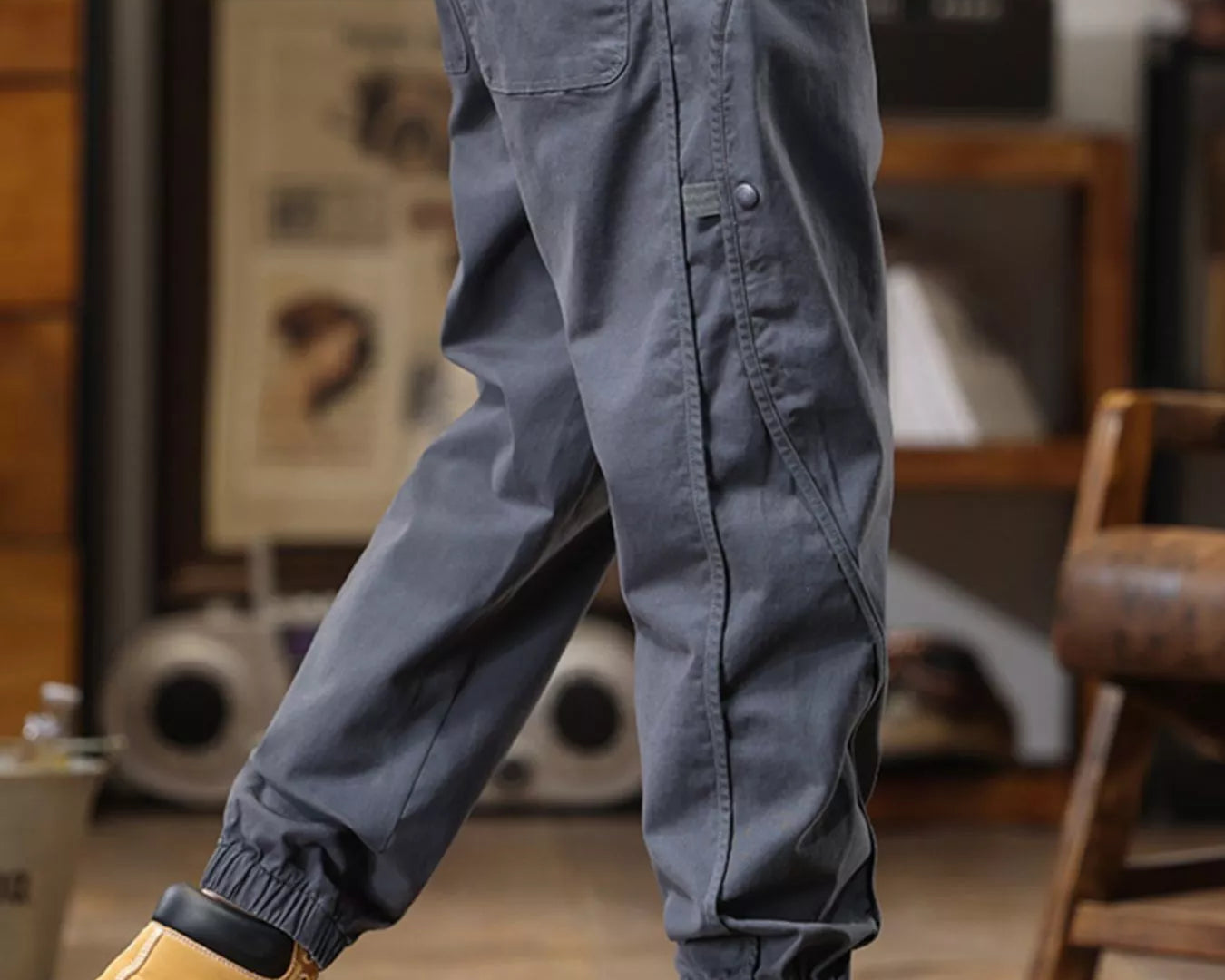 NEWYORKLISTED ATLAS MEN's COLLECTION: Person wearing gray cargo pants and yellow boots in a room with furniture and decor.