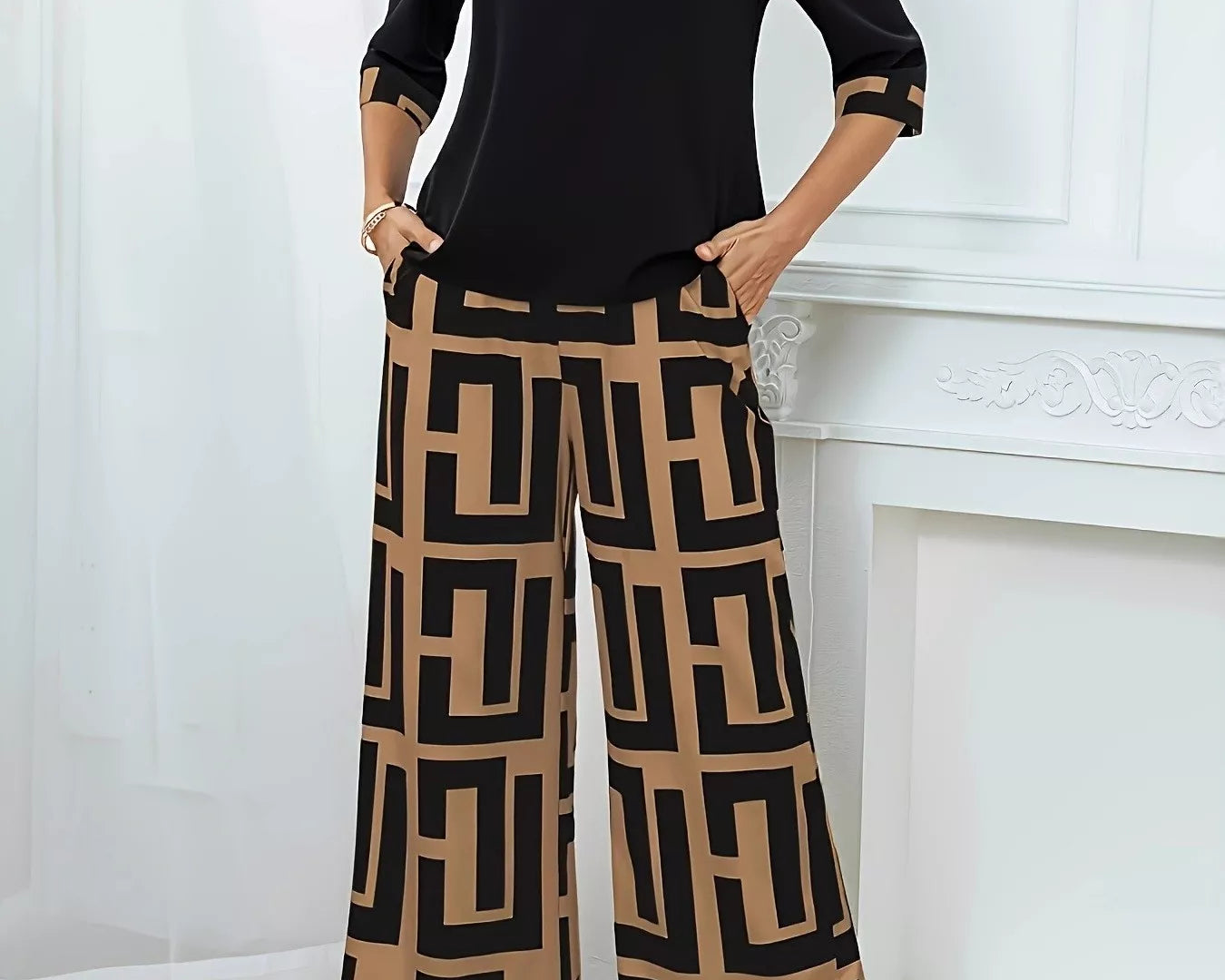 NEWYORKLISTED STYLE COLLECTION: Woman wearing a black top and tan colored patterned pants standing against a white wall.
