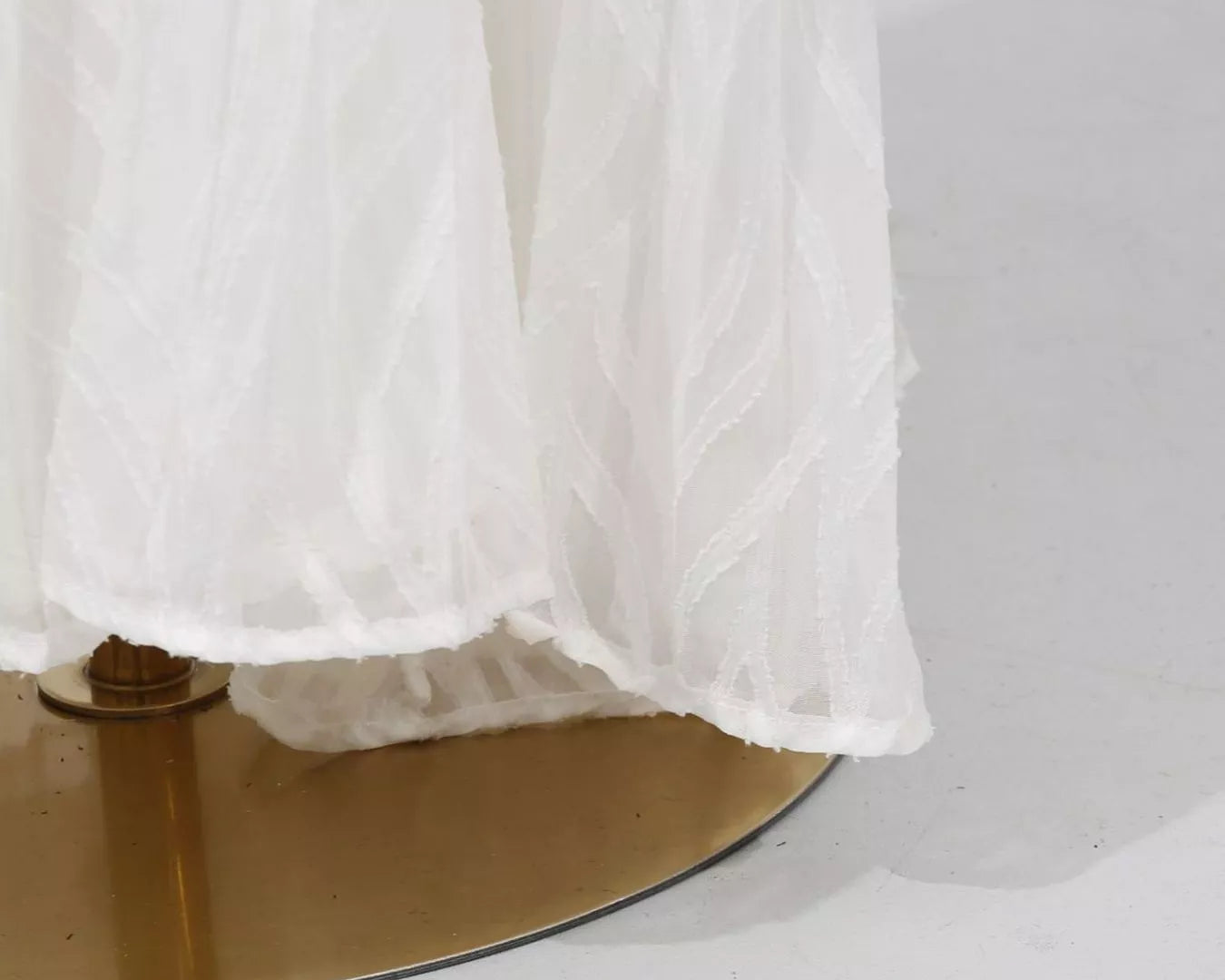 NEWYORKLISTED STYLE COLLECTION: White sheer fabric draped over a gold circular object on a white background