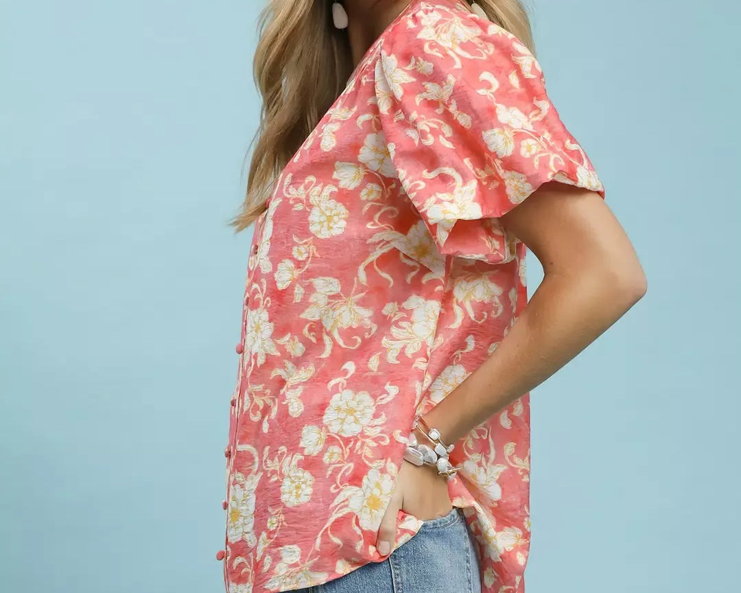 NEWYORKLISTED STYLE COLLECTION: Woman wearing a pink floral blouse and denim shorts against a light blue background