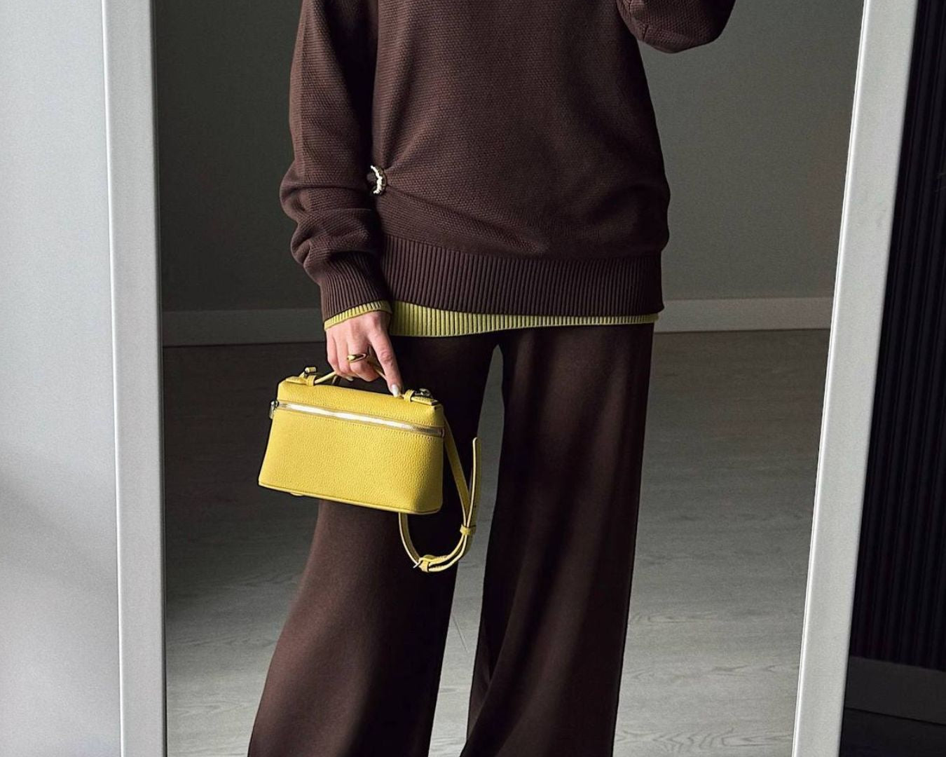 NEWYORKLISTED Comfort Collection: Person wearing a brown outfit with a yellow handbag in front of a mirror.