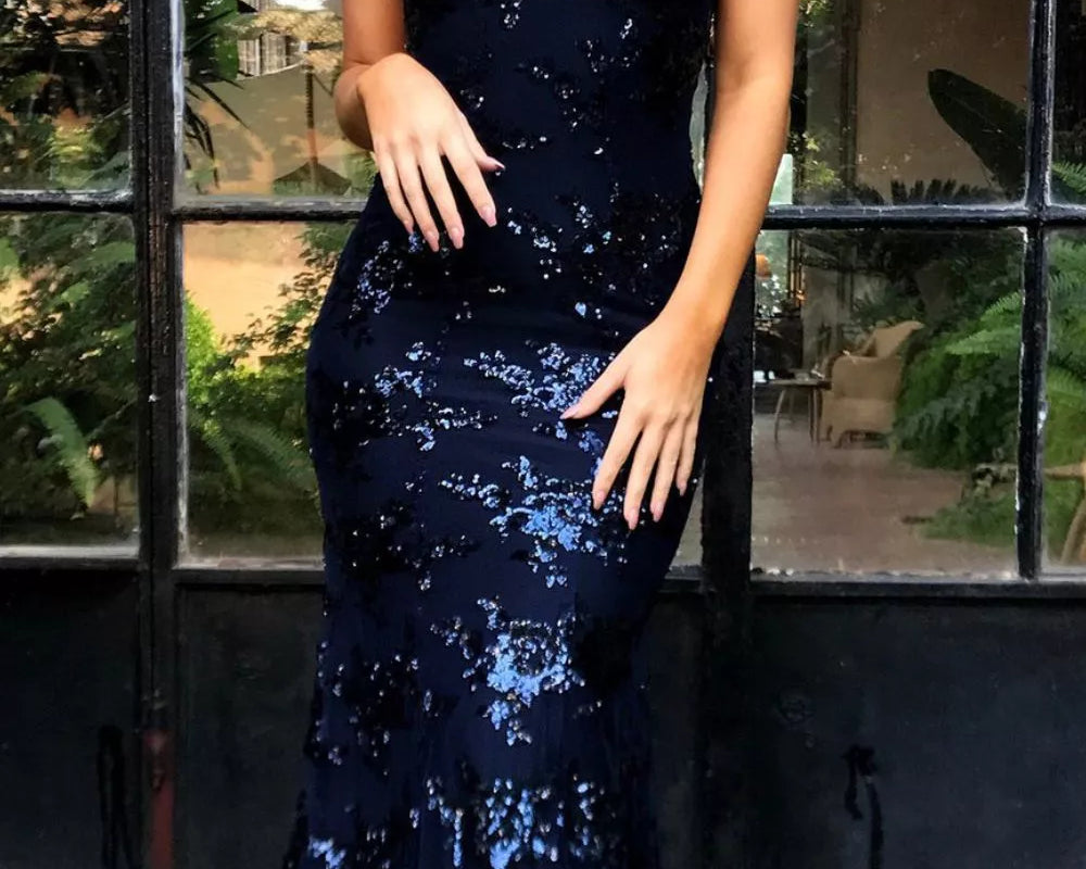 NEWYORKLISTED STYLE COLLECTION: Woman wearing a navy blue sequin dress standing in front of a glass door.