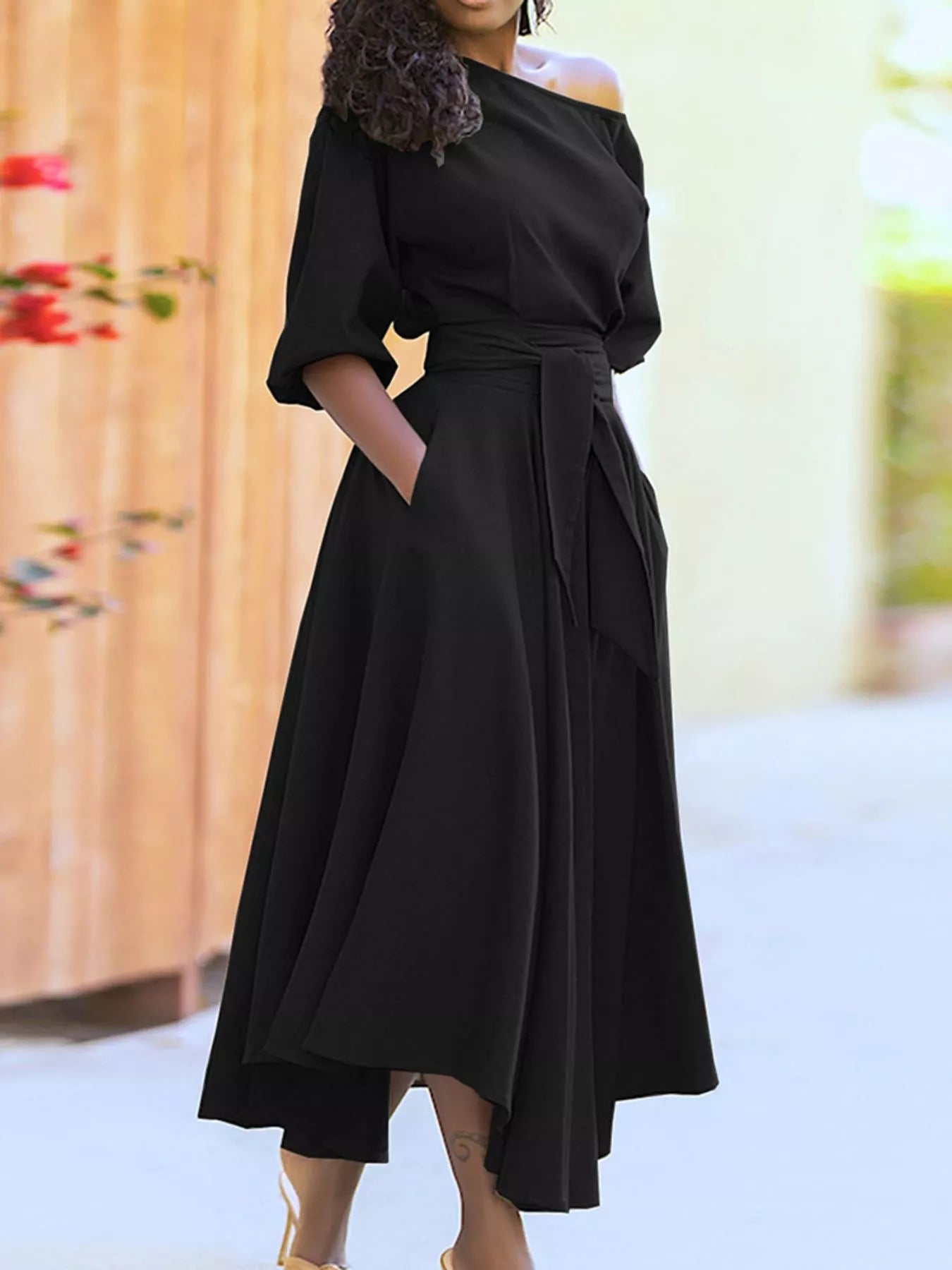 NEWYORKLISTED STYLE COLLECTION: Person wearing a black off-shoulder dress with a blurred floral background