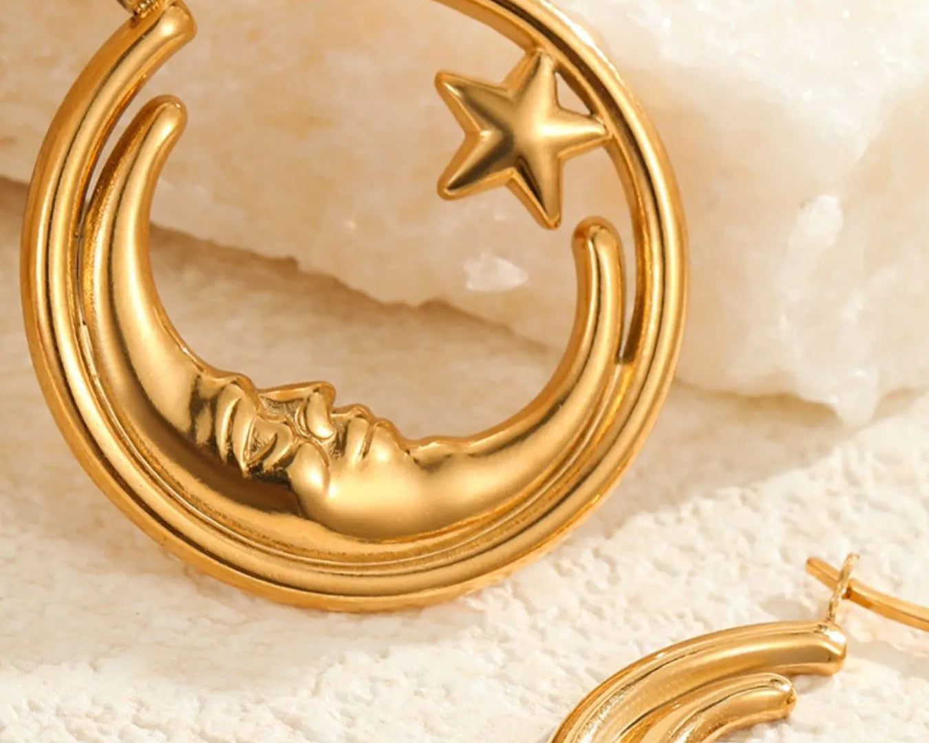 Gold hoop earrings with moon and star design on a textured beige surface- NEWYORKLISTED STYLE COLLECTION