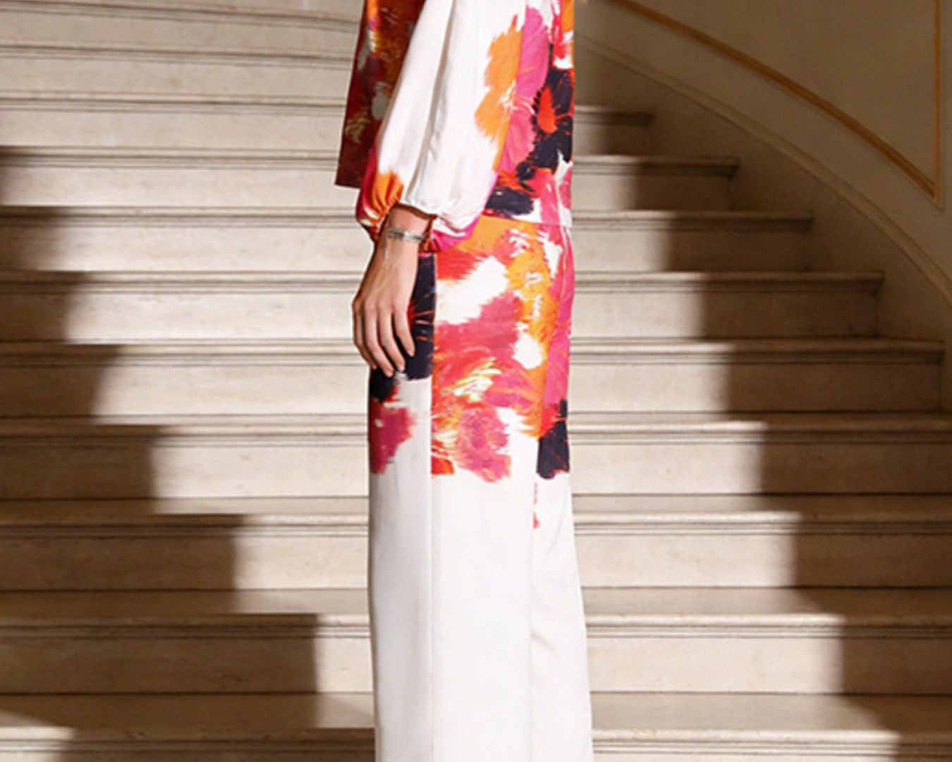 NEWYORKLSITED STYLE COLLECTION: Woman wearing a colorful off-shoulder dress standing on a staircase.