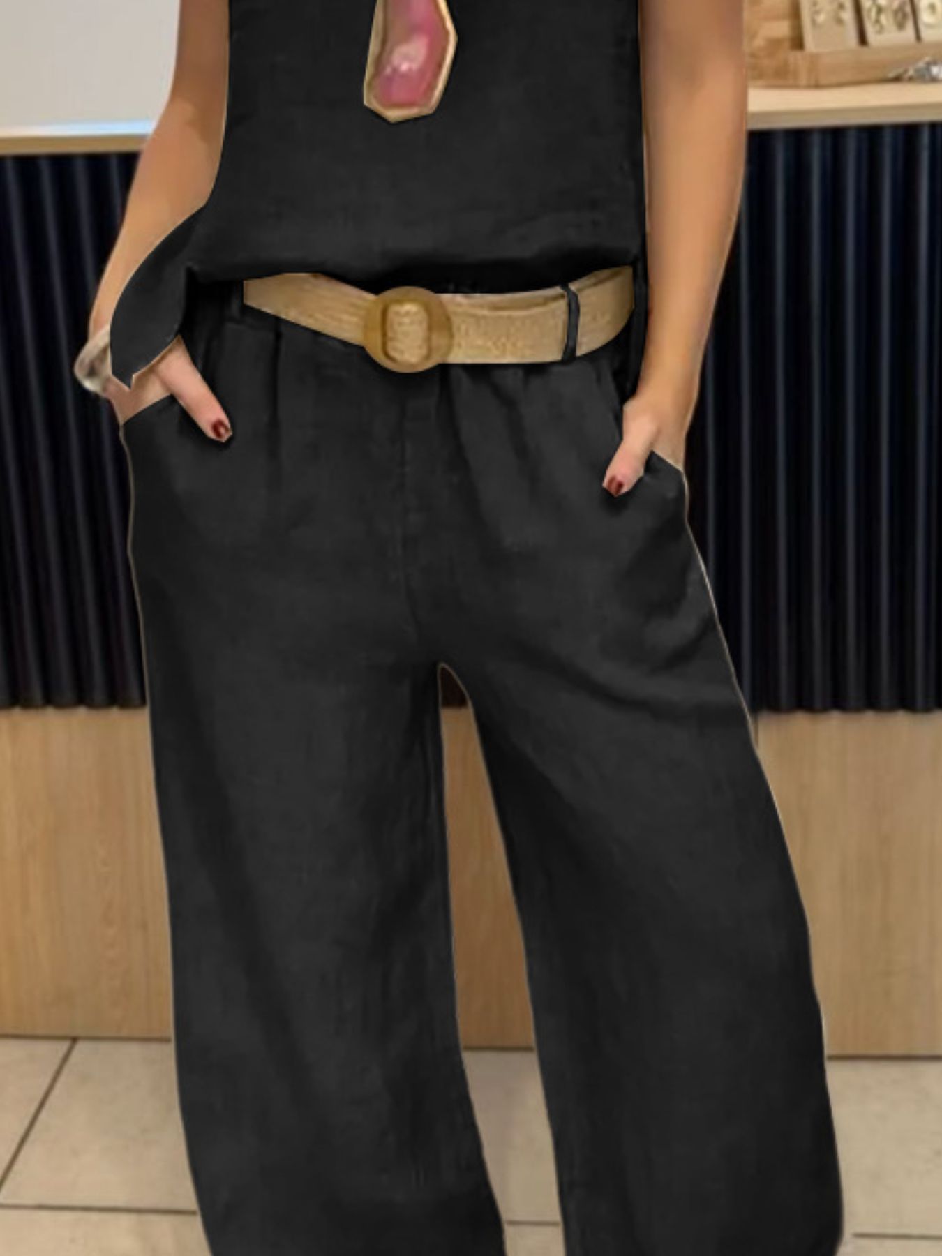 NEWYORKLISTED COMFORT COLLECTION: Person wearing a black sleeveless top and wide-leg black pants with a beige belt.