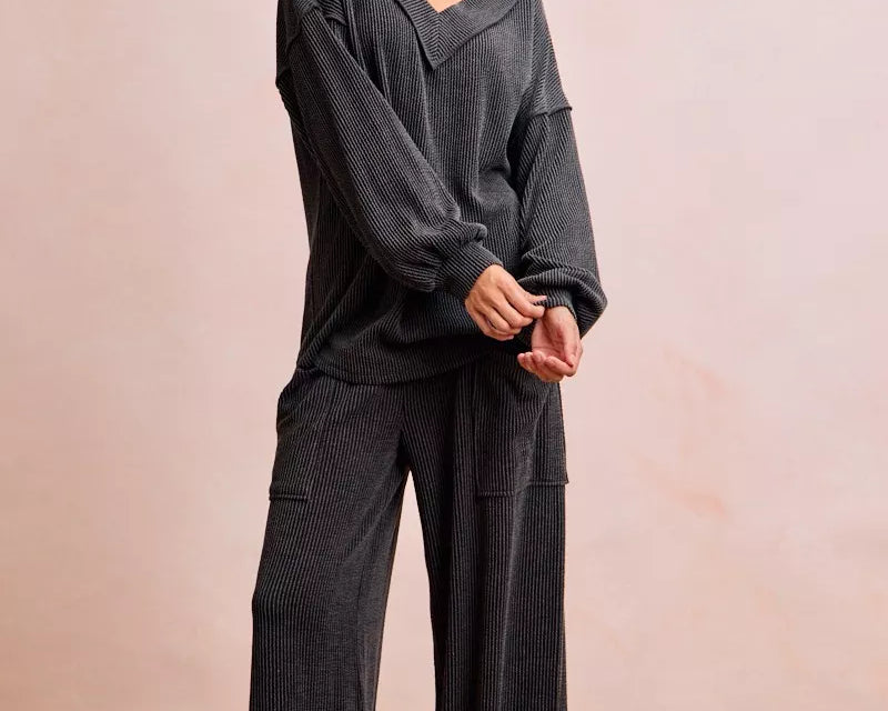 NEWYORKLISTED Comfort Collection: Woman wearing a dark gray outfit with wide-leg pants against a plain background