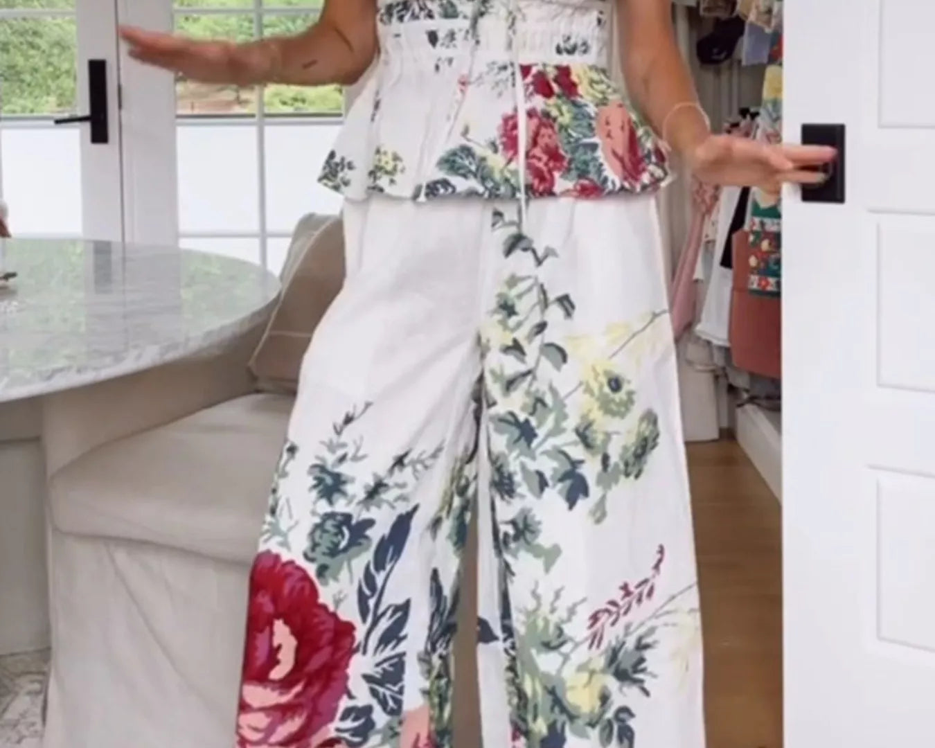 NEWYORKLISTED STYLE COLLECTION: Woman wearing a floral strapless top and wide-leg pants in a room with a white door and window.