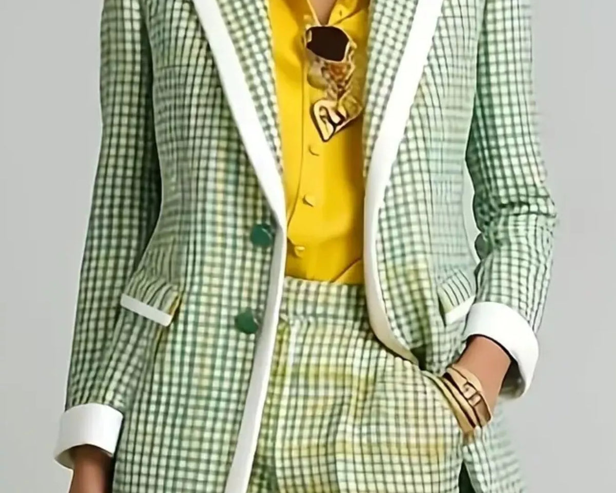 NEWYORKLISTED STYLE COLLECTION: A model wearing a green and white checkered blazer with white contrast piping, matching checkered trousers, a bright yellow shirt, and gold jewelry against a light gray background.