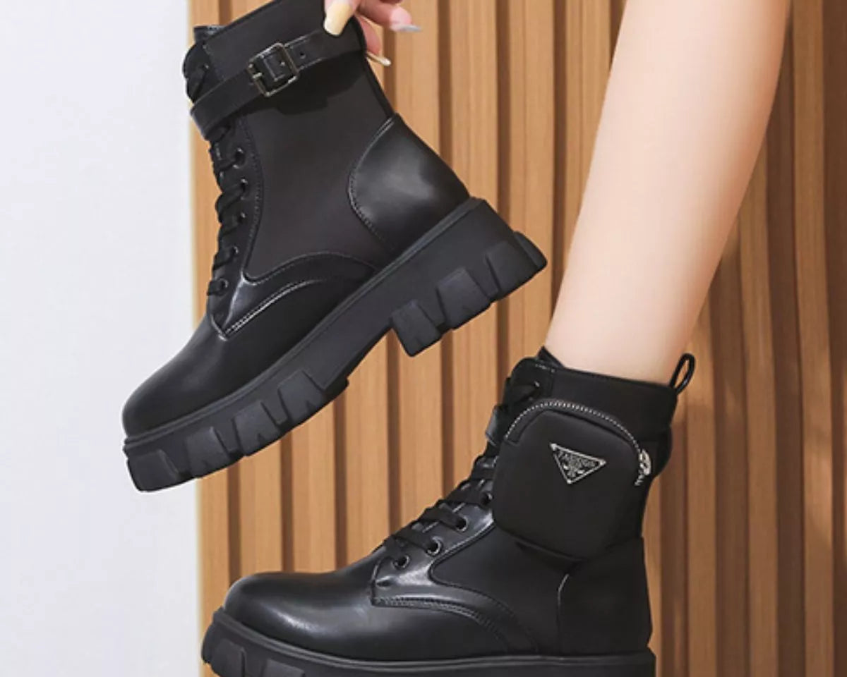 NEWYORKLISTED SHOE COLLECTION: Black boots being held up against a neutral background