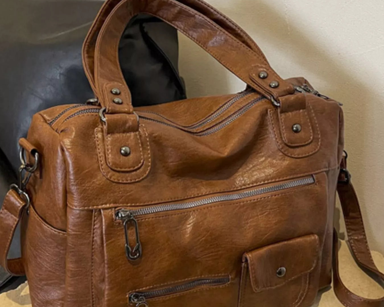 NEWYORKLISTED STYLE COLLECTION: Brown leather handbag on a cardboard surface with a neutral background