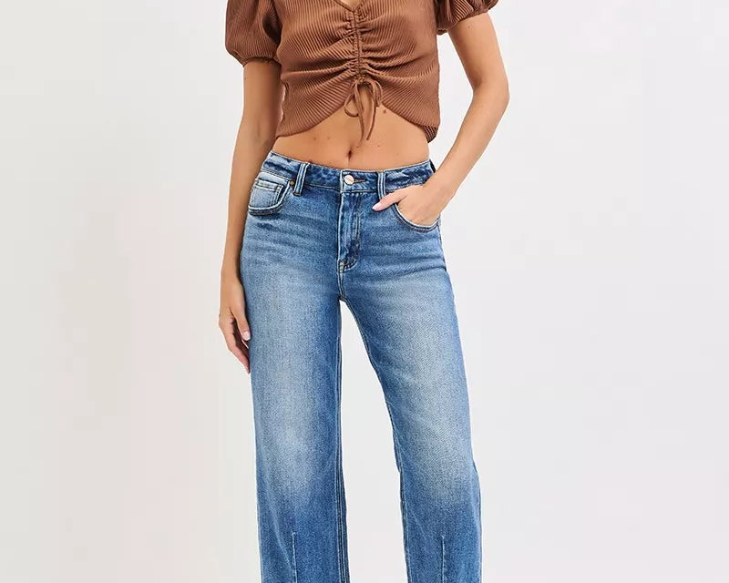 NEWYORKLISTED DENIM COLLECTION: Woman wearing a brown top and blue jeans on a white background