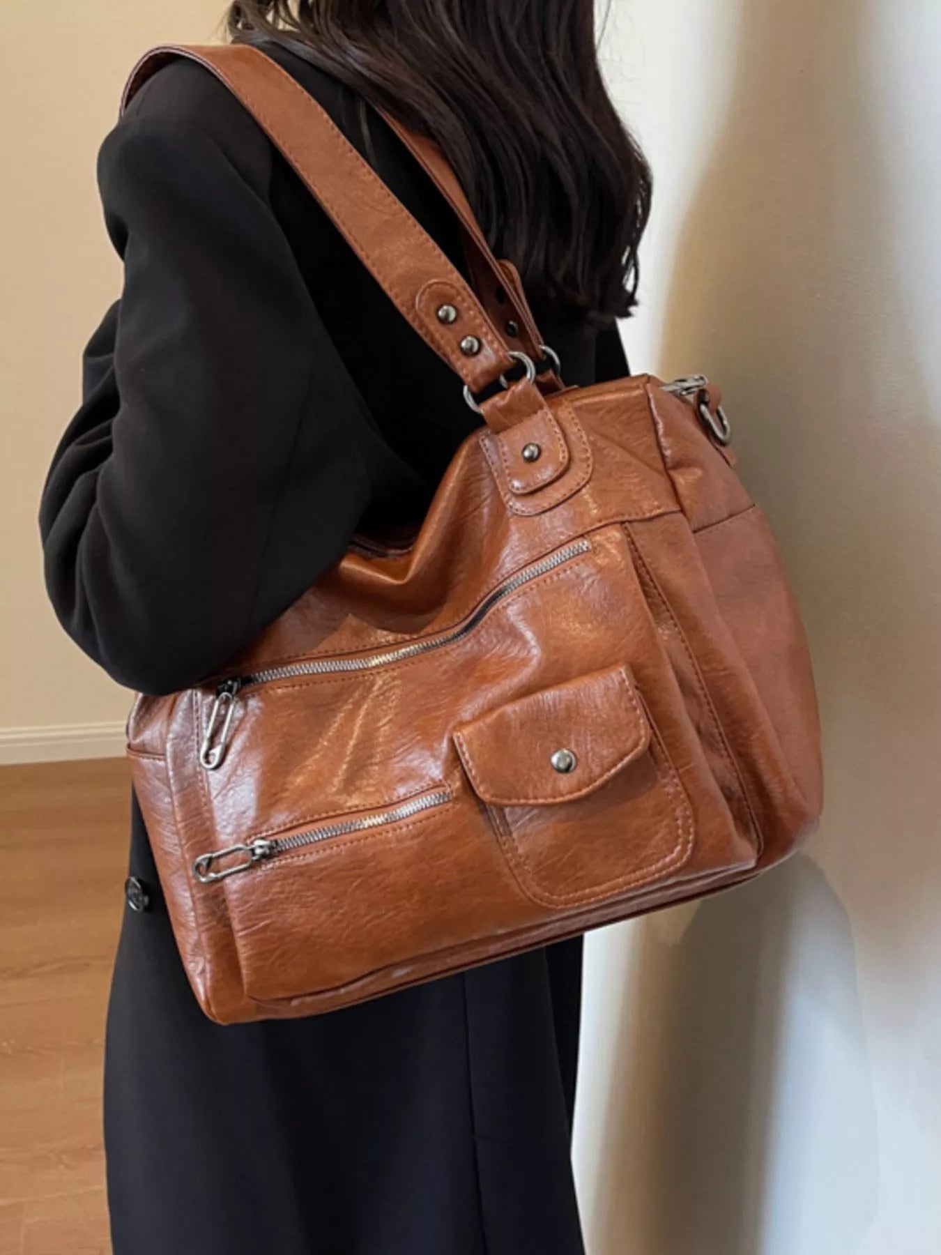 NEWYORKLISTED STYLE COLLECTION: Brown leather handbag worn by a person against a neutral background