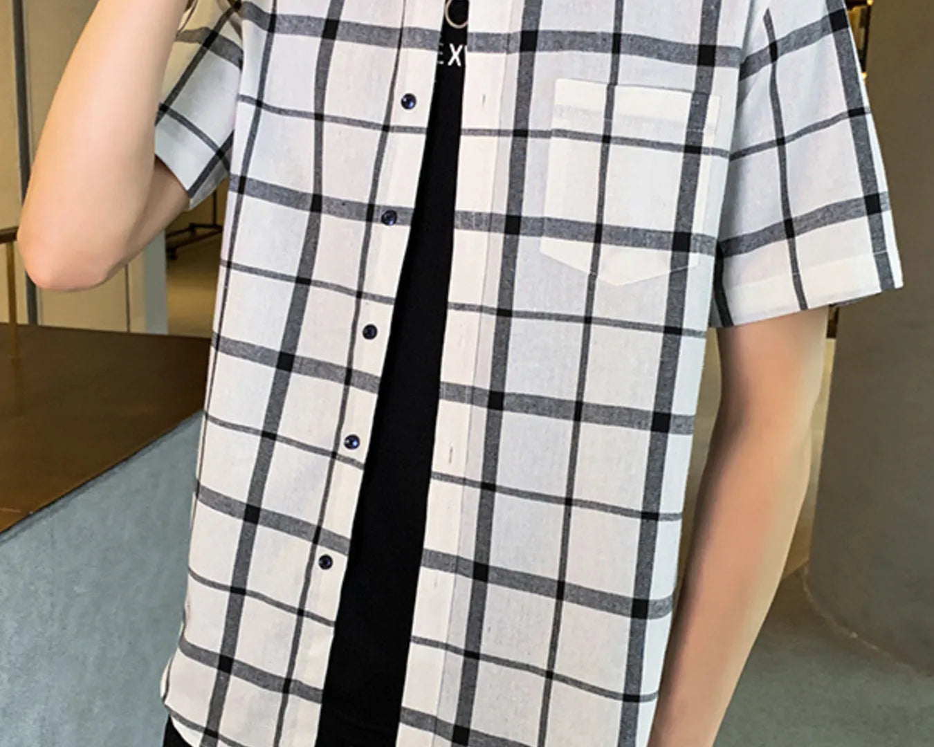 NEWYORKLISTED ATLAS MEN'S COLLECTION: Person wearing a black and white checkered shirt with a blurred indoor background