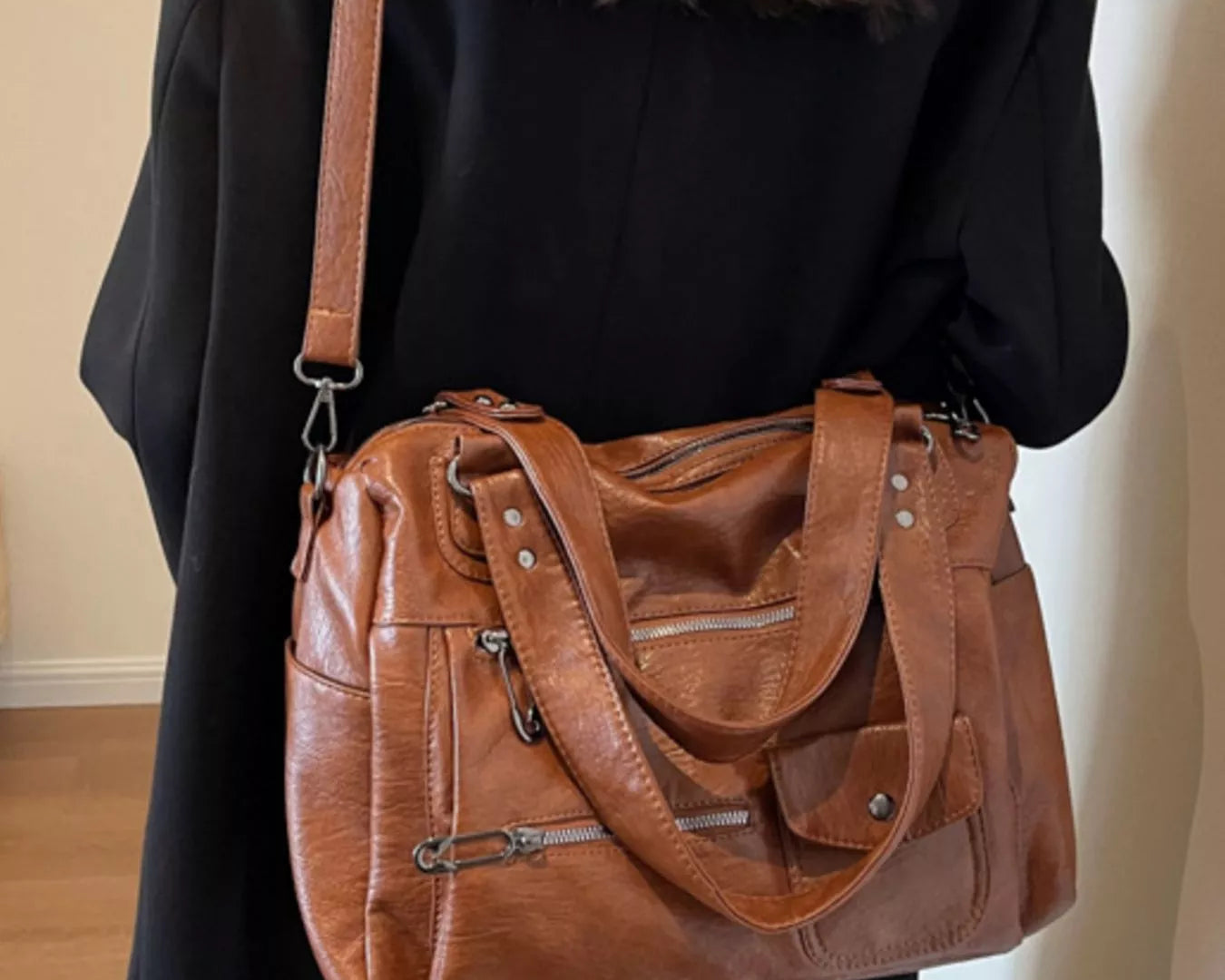 NEWYORKLISTED STYLE COLLECTION: Person wearing a brown leather handbag over one shoulder against a neutral background