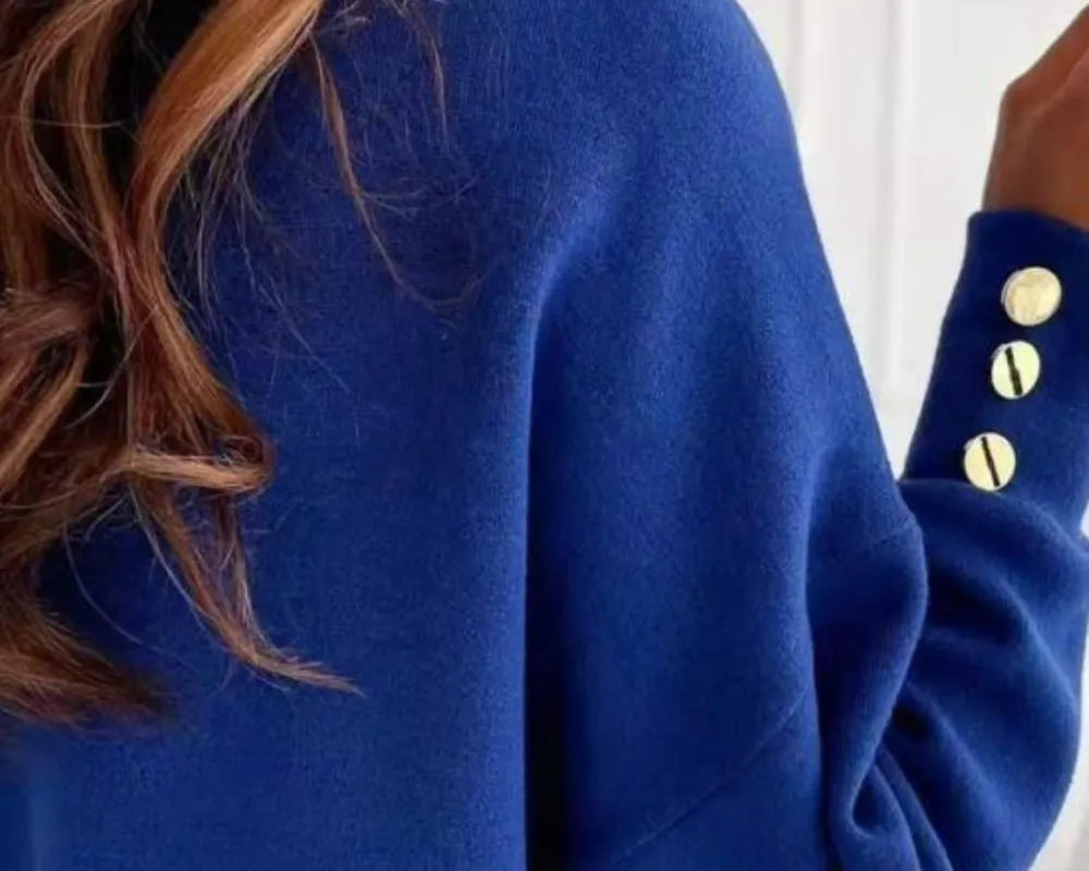 NEWYORKLISTED STYLE COLLECTION: Blue sweater with gold buttons worn by a person, blurred background