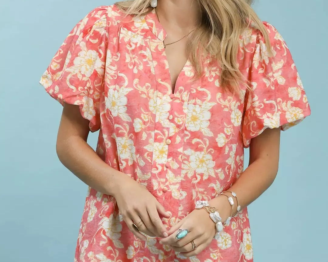 NEWYORKLISTED STYLE COLLECTION: Woman wearing a pink floral blouse and denim shorts against a light blue background