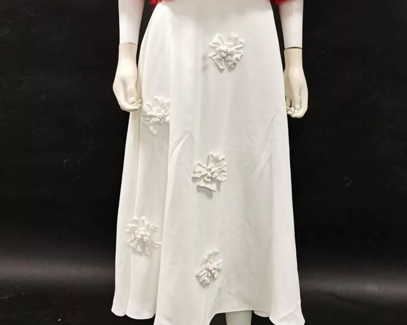 NEWYORKLISTED STYLE COLLECTION: Mannequin wearing a red floral top and white skirt with floral embellishments on a black background